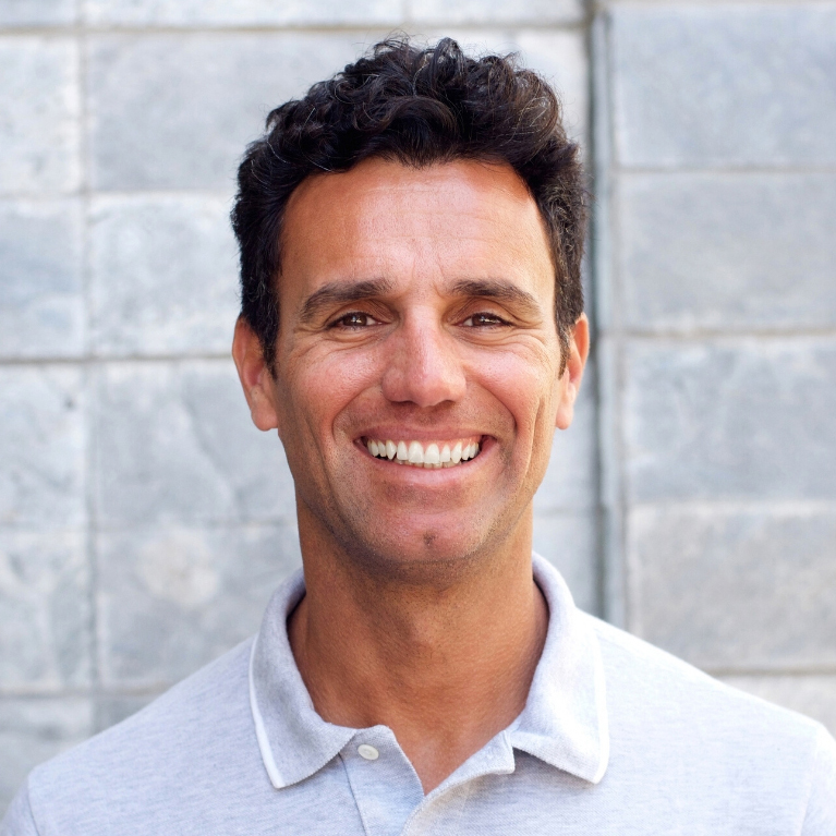 A middle-aged man with black hair is smiling at the camera.