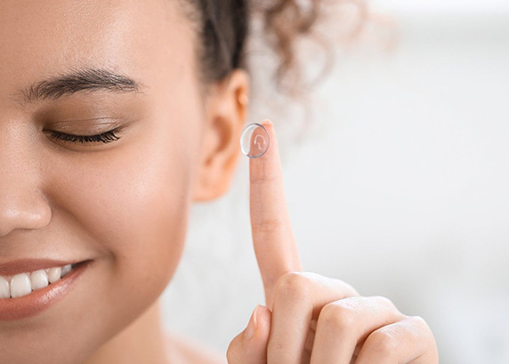 woman happy holding contact lens