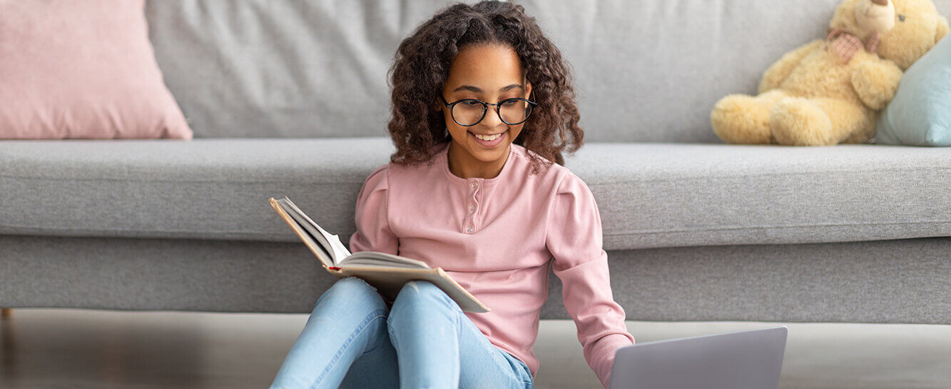 child with eyeglasses using laptop and book