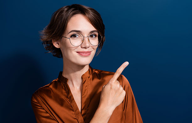 A woman in front of a blue background pointing.